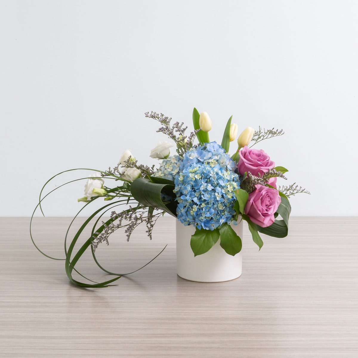 Lizzy in blue arrangement with blue hydrangea, cool water roses, and white lisianthus