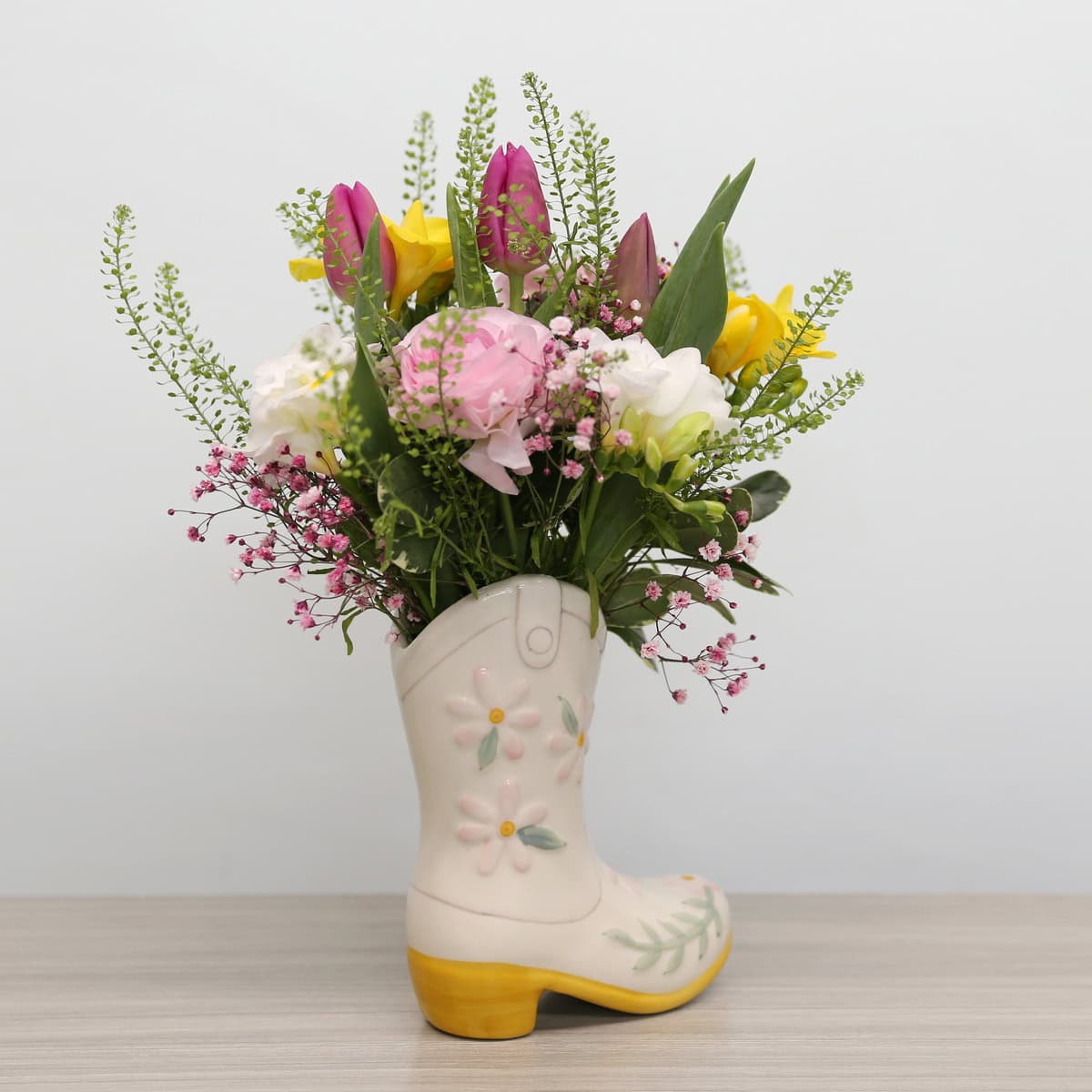 Mother's Day floral arrangement with tulips, ranunculus, freesias, and lisianthus in a ceramic boot vase