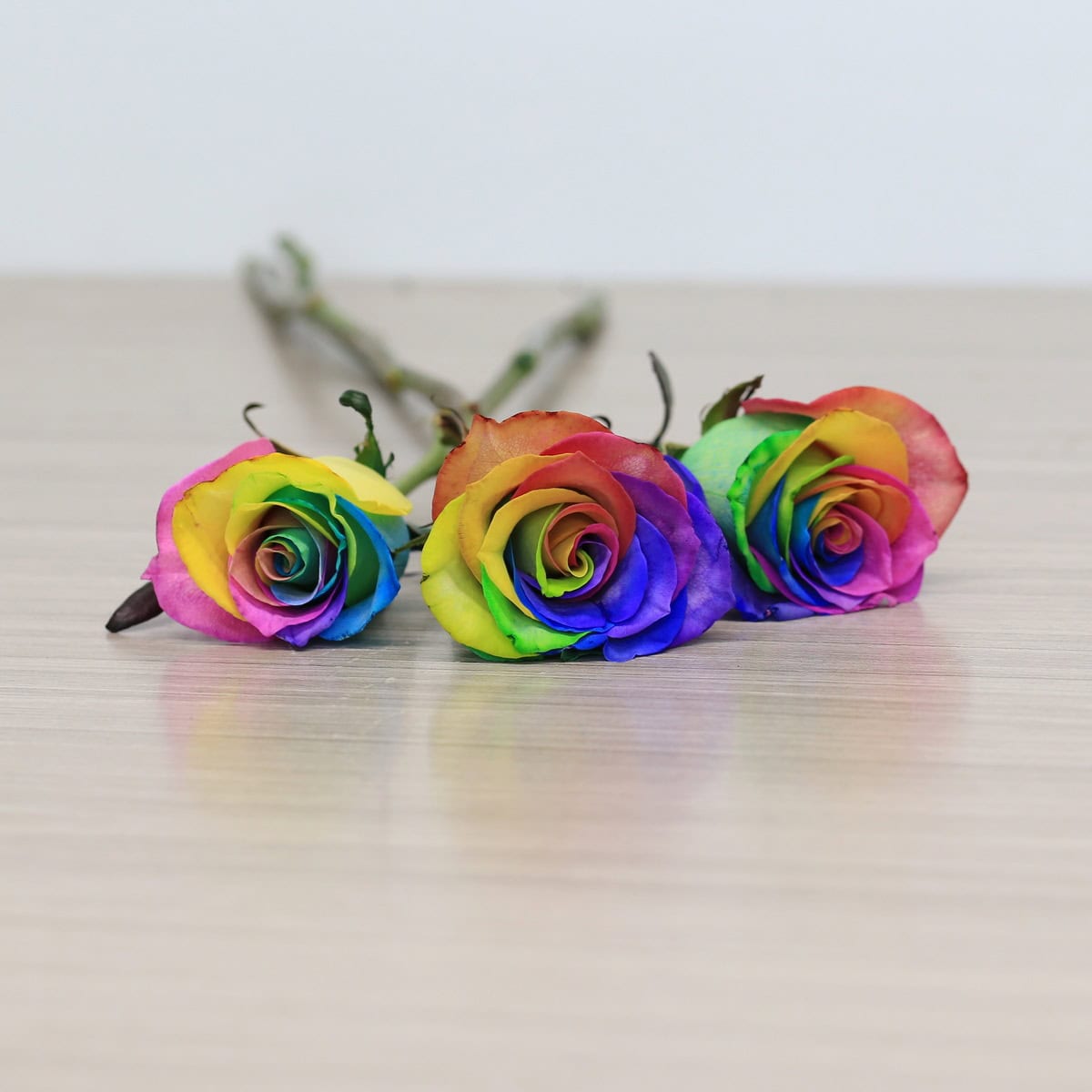 rainbow roses arranged bouquet with greenery