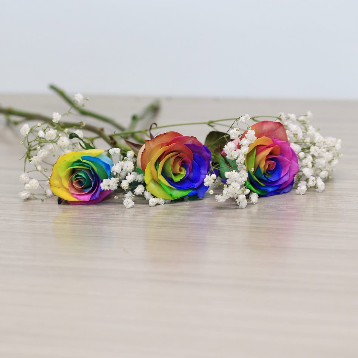 rainbow roses arranged bouquet with greenery and floral accents