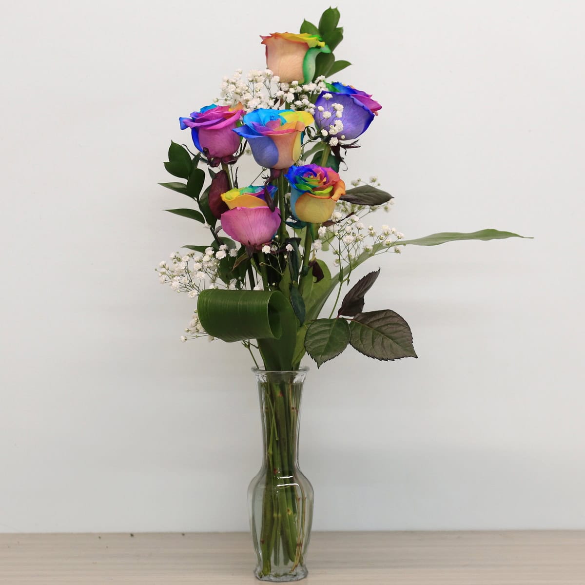 rainbow roses arranged bouquet with greenery and floral accents