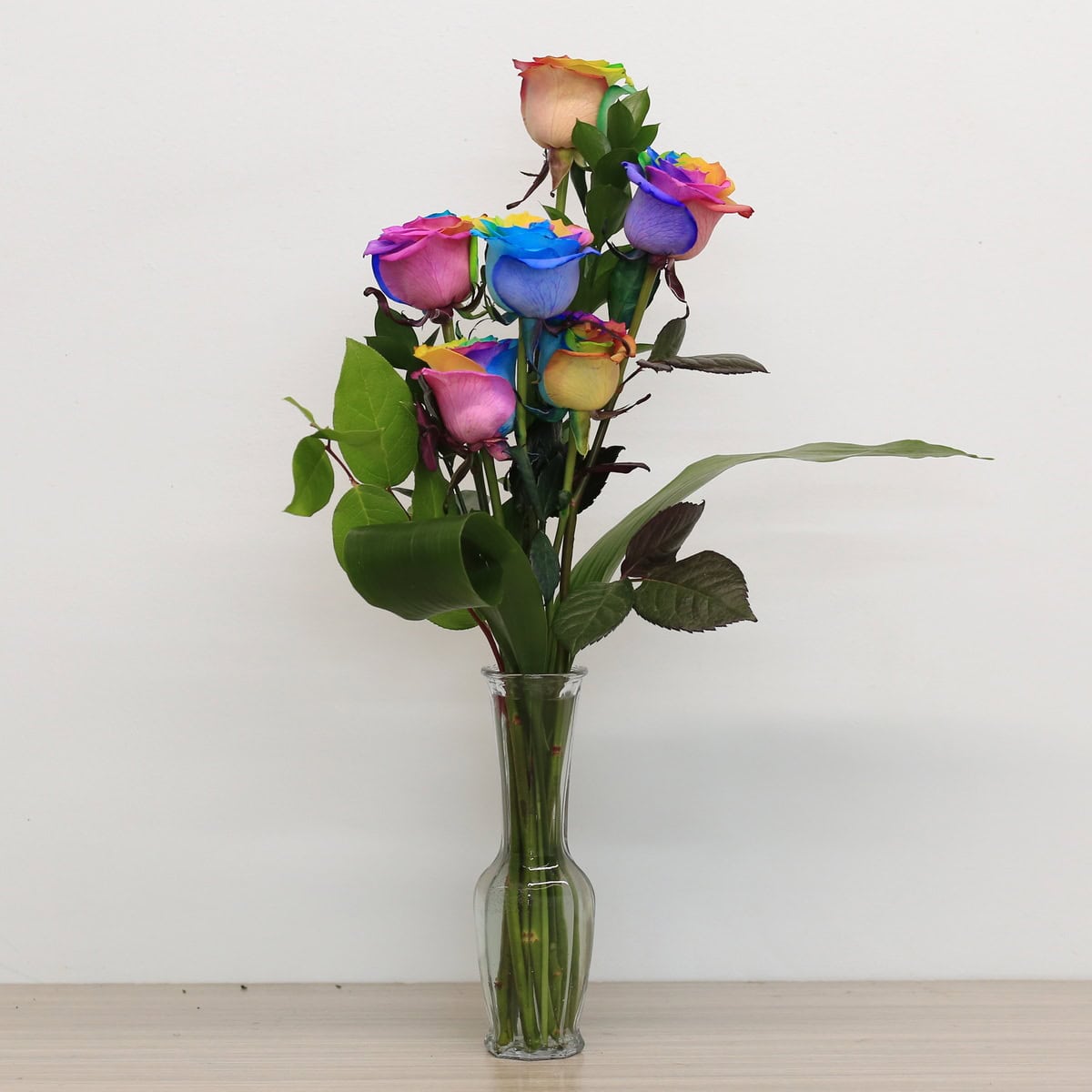 rainbow roses arranged bouquet with greenery