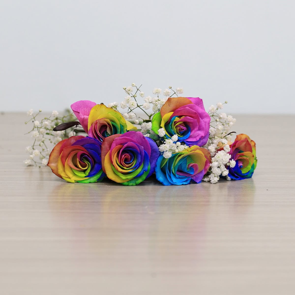 rainbow roses arranged bouquet with greenery and floral accents
