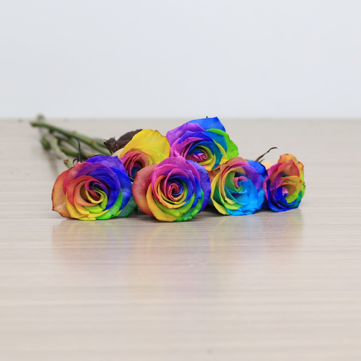 rainbow roses arranged bouquet with greenery