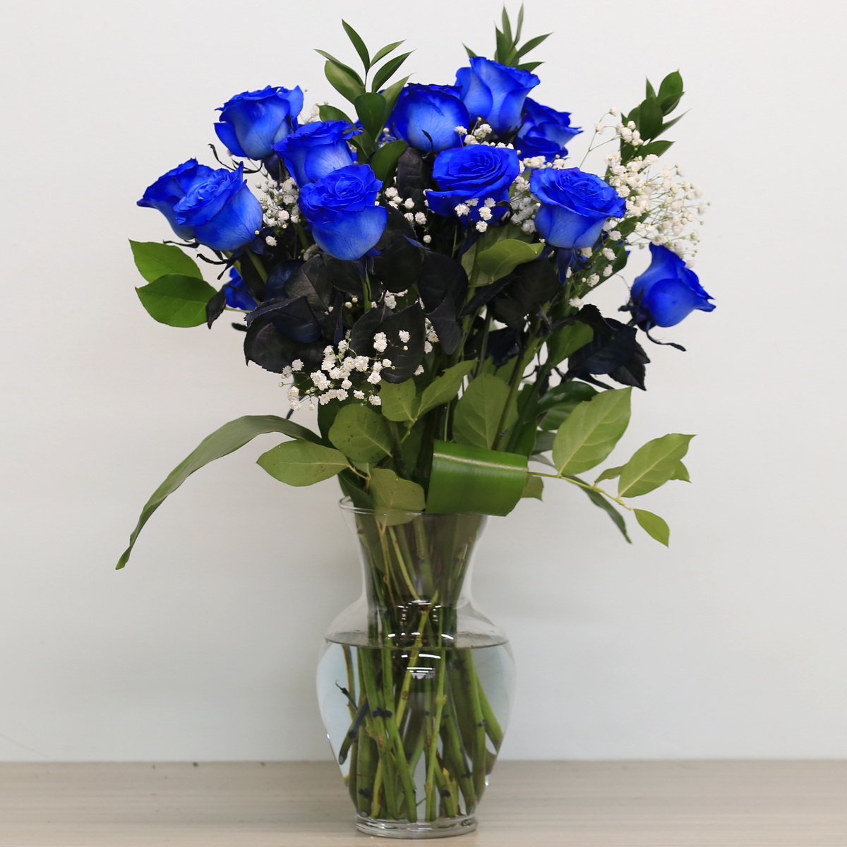 Blue roses with greenery and floral accents in vase