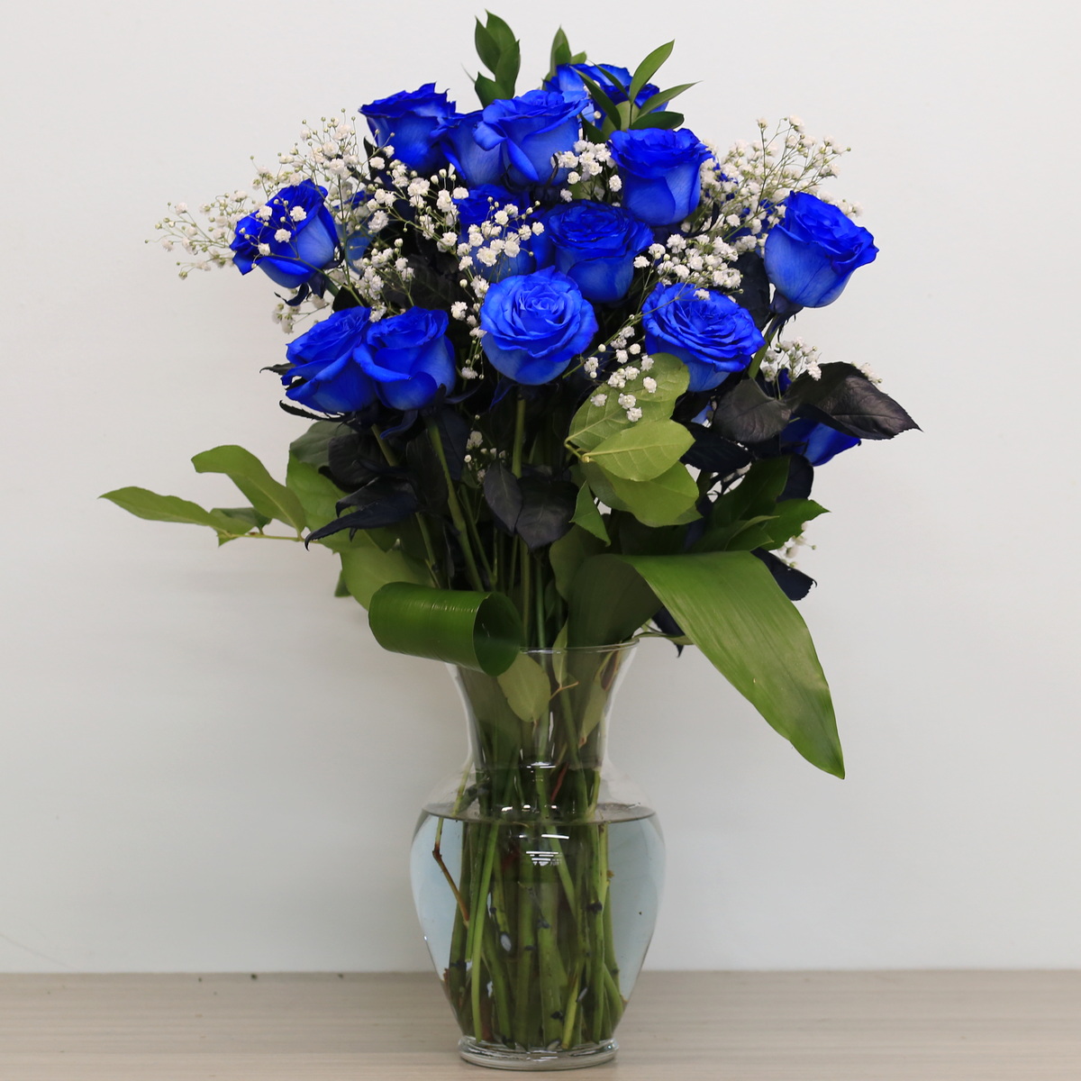 Blue roses with greenery and floral accents in vase