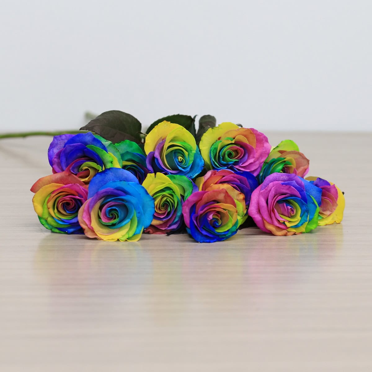 rainbow roses arranged bouquet with greenery