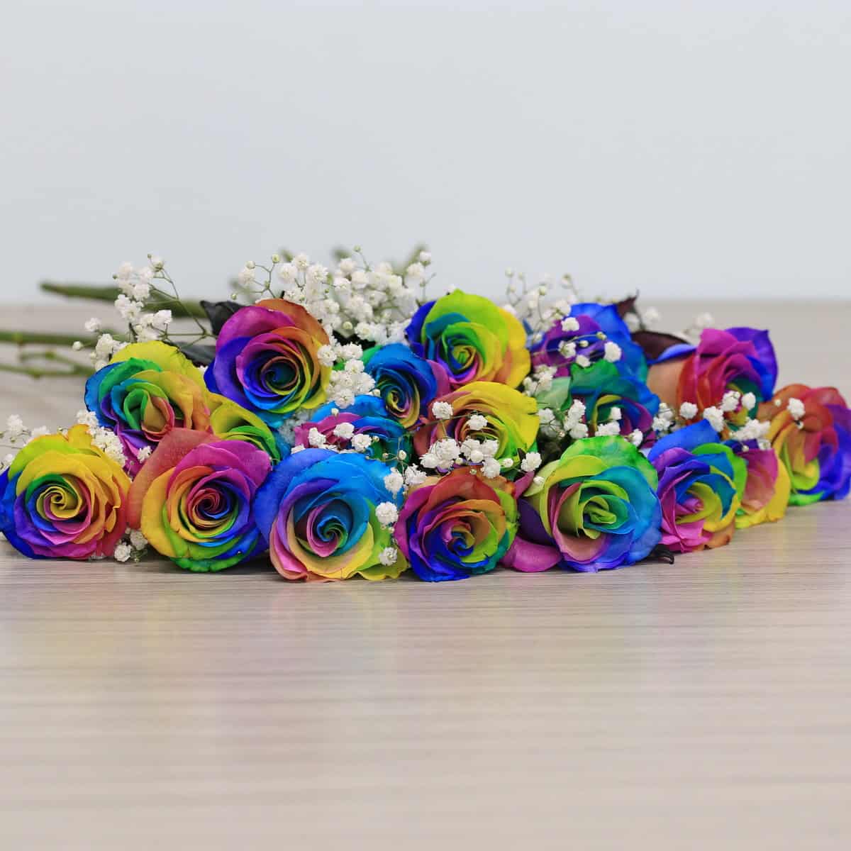 rainbow roses arranged bouquet with greenery and floral accents
