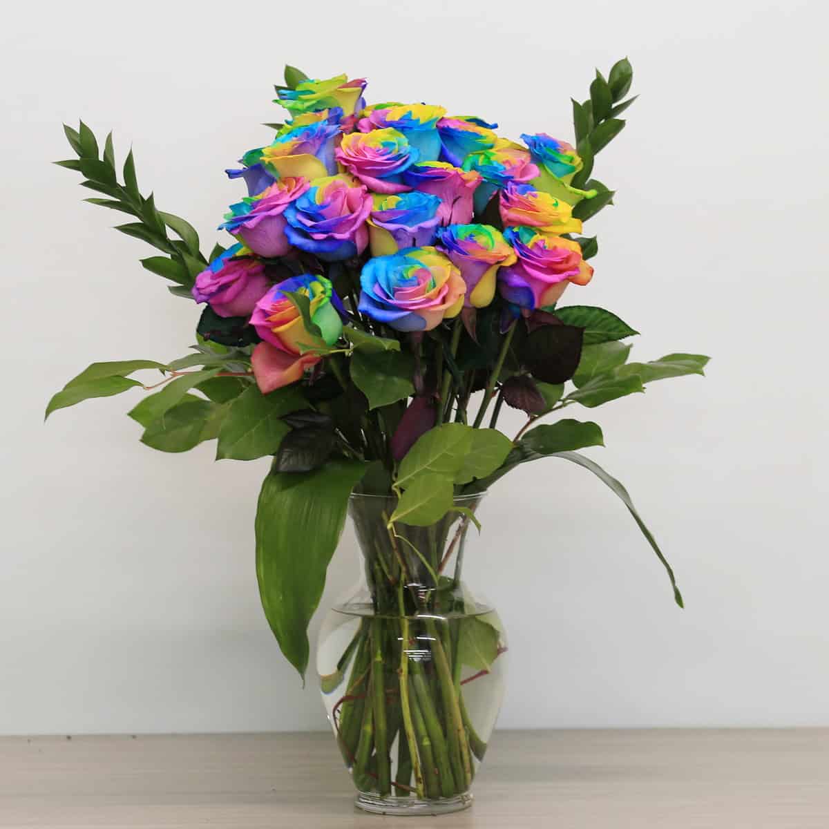 rainbow roses arranged bouquet with greenery