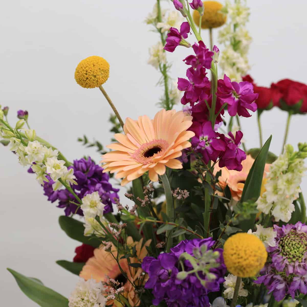 Close-up of Field of Harmony arrangement highlighting roses, gerbera and vertical stock stems.