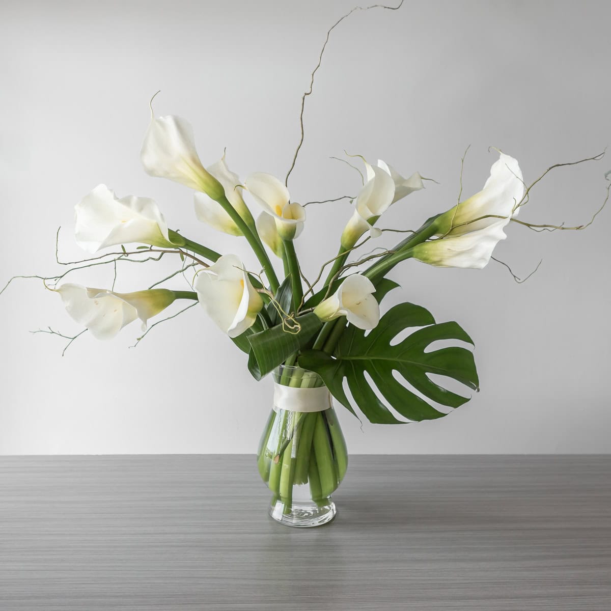 Large white calla lily arrangement in glass vase centerpiece