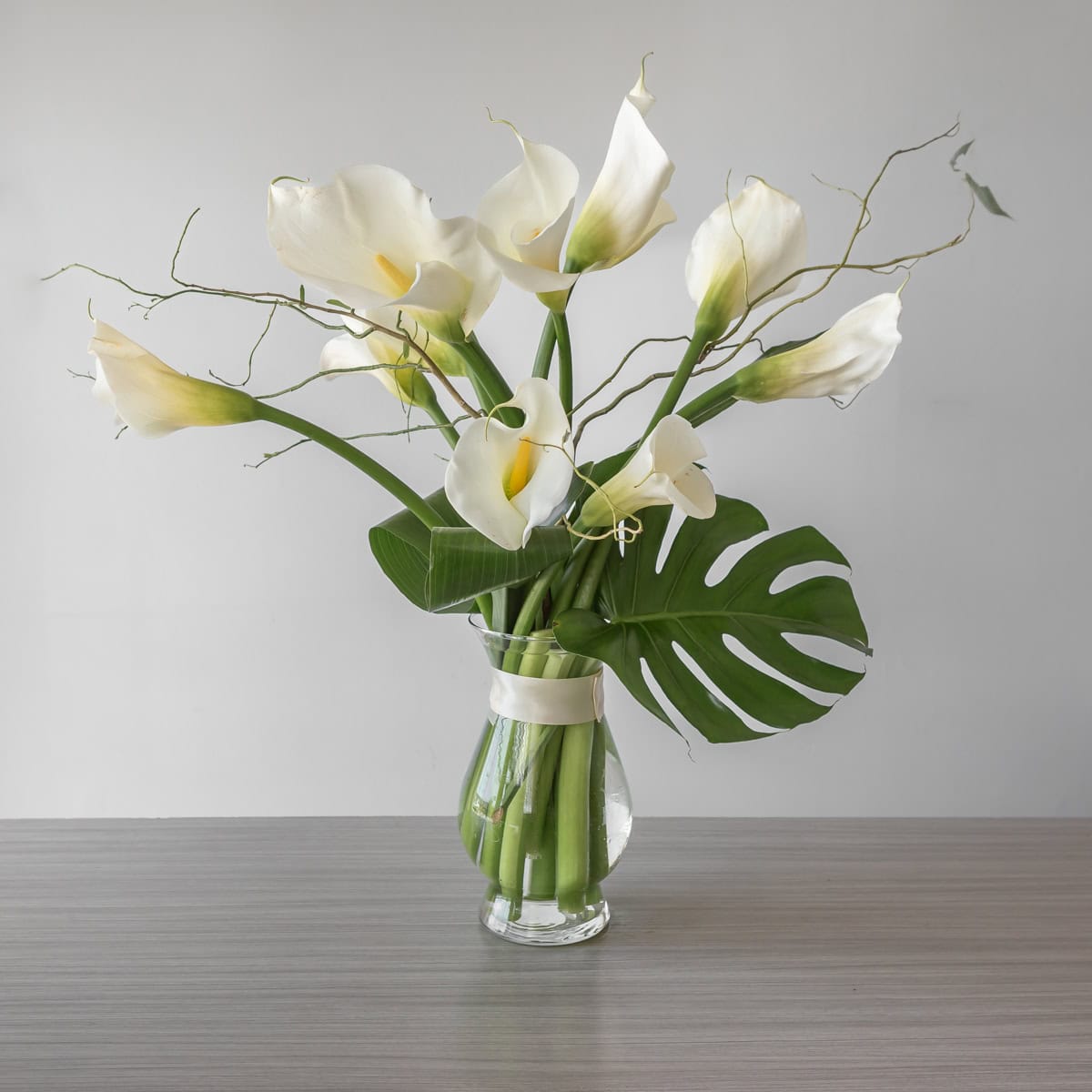 Large white calla lily arrangement in clear vase